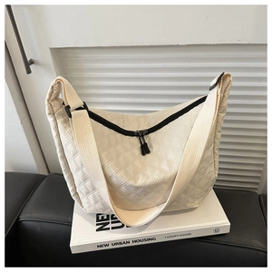 Close-up of beige quilted nylon crossbody bag featuring diamond stitching and wide strap
