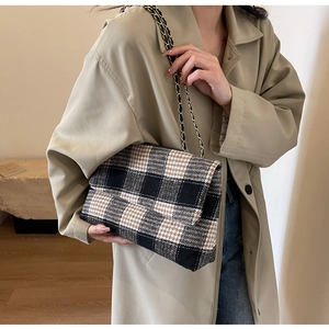 Dettaglio della borsa in tweed a quadretti con tracolla a catena su cappotto khaki
