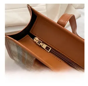Detailaufnahme des glatten Goldreißverschlusses und Karostoffs der Vintage-Schultertasche