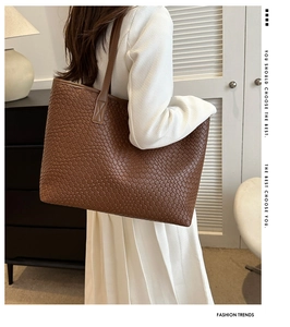 Détail de la texture en cuir tressé marron foncé d'un grand sac cabas avec bandoulière