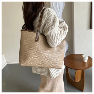 Detail of a large woven tote bag in beige with brown straps for daily commuting