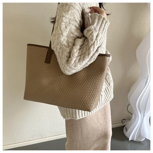 Modella che indossa una borsa tote intrecciata kaki con manici in pelle in stile moderno