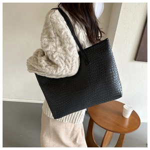 Dettaglio ravvicinato della trama intrecciata di una grande borsa tote nera in pelle