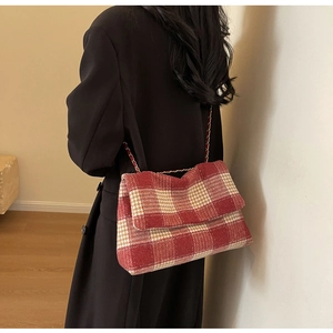 Dettaglio della borsa a tracolla in tweed a quadri rossi e beige su un cappotto nero