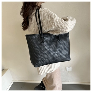 Close-up of black woven tote bag showing texture and reinforced shoulder straps