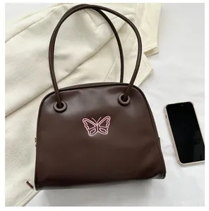 Top view of dark brown shell bag with pink butterfly and phone for size reference