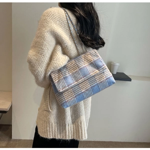 Borsa a tracolla in tweed a quadri blu e beige indossata da una modella elegante
