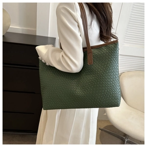 Dettaglio della borsa tote intrecciata verde scuro con manici in pelle marrone su modella
