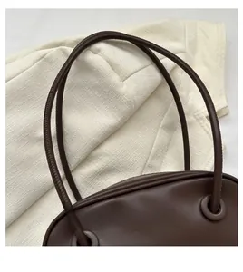 Detail of slim double handles on a vintage dark brown shell shoulder bag for women