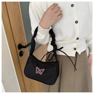 Dettaglio della borsa a mezzaluna in nylon nero con ricamo farfalla rosa e manico arricciato