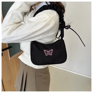 Dettaglio borsa a mezzaluna nera con ricamo farfalla rosa e tracolla con volant eleganti