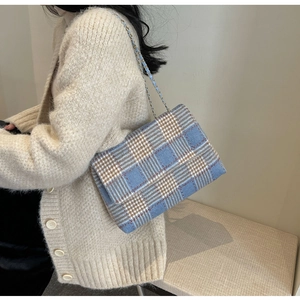 Dettaglio di una borsa a tracolla in tweed a quadri blu e bianchi con catena oro