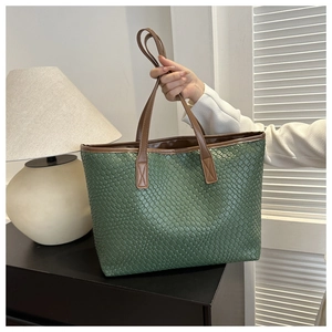 Detail of green woven tote bag with brown leather handles for a minimalist style