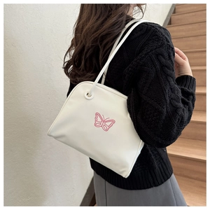 Detailed view of a white leather shoulder bag with sweet pink butterfly embroidery