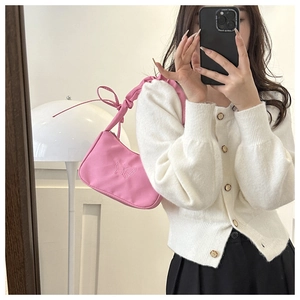 Detalle de bolso rosa con bordado de mariposa y correa de hombro con lazo fruncido