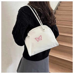 Detail of white faux leather shoulder bag featuring delicate pink butterfly embroidery
