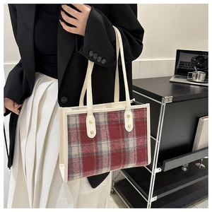 Detail der rot-weiß karierten Tweed-Tasche mit cremefarbenen Ledergriffen und Goldnieten