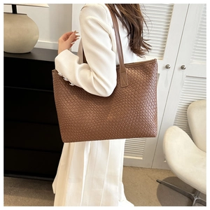 Détail du sac cabas marron tissé présentant une texture croisée et des anses élégantes