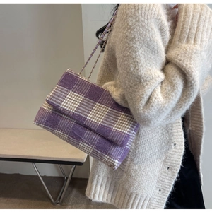 Dettaglio della borsa a tracolla in tweed a quadri viola e beige con catena dorata su modella