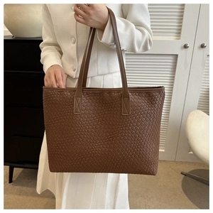 Gros plan du sac cabas en cuir tressé marron montrant la texture et la bandoulière