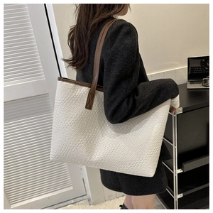 Detail of cream woven tote bag with brown leather handles showing large capacity