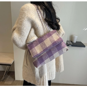 Dettaglio della borsa in tweed a quadri viola con tracolla a catena su una modella