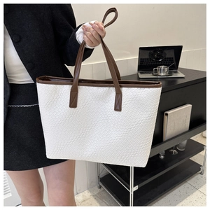 Gros plan du cabas tissé blanc avec anses en cuir marron dans un décor de bureau moderne