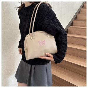 Detail of a minimalist cream shoulder bag with pink butterfly embroidery on smooth leather