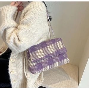 Dettaglio della borsa in lana a quadri viola su un cardigan in maglia beige chiaro