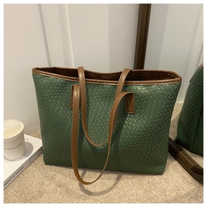 Macro detail of dark green woven tote bag with brown leather handles and textured surface