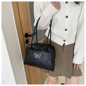 Detail of black shell shoulder bag with pink butterfly embroidery and slender handles