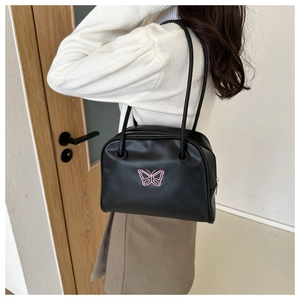 Detailed side view of a minimalist black shoulder bag with pink butterfly embroidery