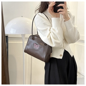 Detail of dark brown leather shoulder bag featuring pink butterfly embroidery and gold zipper