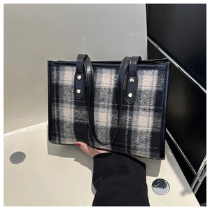 Detail der Woll-Tote-Bag mit Karomuster, Textur und robusten Ledergriffen