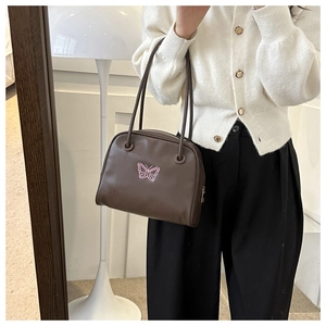 Detail of dark brown shell shoulder bag with pink butterfly embroidery and dual handles