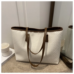 Close-up of white woven tote bag with brown leather straps and elegant interior decor
