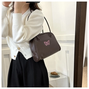 Detail of a brown leather shoulder bag with pink butterfly embroidery and Y2K aesthetic