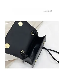 Dettaglio della borsa in pelle nera a grana litchi con chiusura magnetica dorata