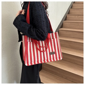 Detail of red and white striped canvas tote bag with fashion leather patch on model