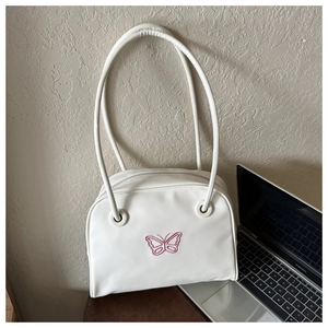 Detailed view of white PU leather bag with pink butterfly embroidery and long shoulder straps