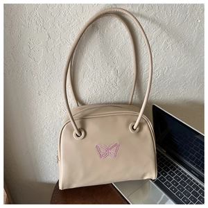 Close-up of a beige faux leather bag featuring pink butterfly embroidery and zipper detail