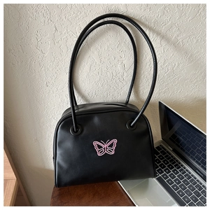 Detail view of black matte leather shell bag featuring pink butterfly embroidery and slim straps
