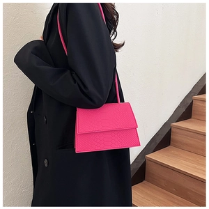 Modella con borsa a tracolla fucsia motivo coccodrillo su un'elegante scala interna