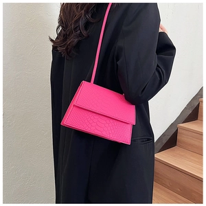 Dettaglio borsa fucsia con stampa coccodrillo su blazer nero con tracolla sottile