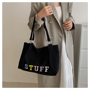 Detail of black corduroy tote bag with colorful STUFF patch and silver metal rings