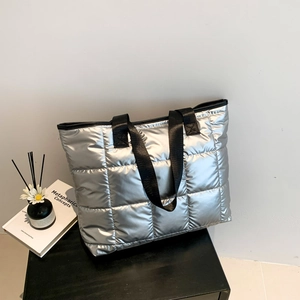 Silver quilted down tote bag with large puffer squares and black textile straps