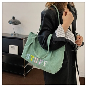 Close-up of mint green corduroy tote bag featuring colorful embroidered STUFF lettering