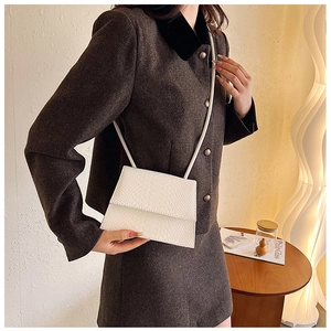 Dettaglio di una mini borsa quadrata bianca con goffratura coccodrillo e patta