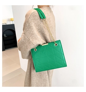 Détail du sac cabas matelassé vert avec chaîne dorée et boucle métallique rectangulaire