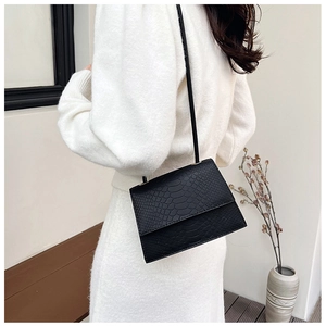 Dettaglio di borsa nera minimalista con elegante trama a motivo coccodrillo goffrato